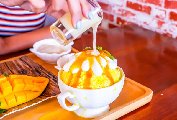 Γυναικείο χέρι ρίχνει ζαχαρούχο συμπυκνωμένο γάλα στον πάγο Bingsu (κορεάτικο επιδόρπιο στυλ) δροσιστικό επιδόρπιο με μάνγκο φρούτα και κολλώδες ρύζι — Φωτογραφία Αρχείου