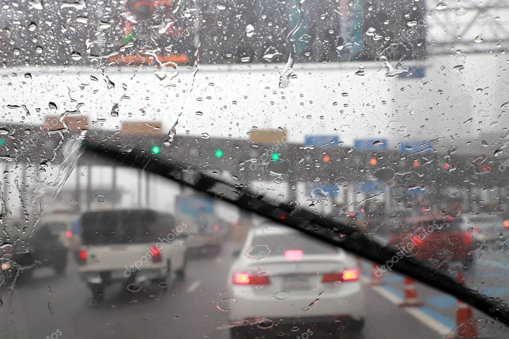 Front view of Driving with car windshield wipers in raining day on the expressway tollgate.
