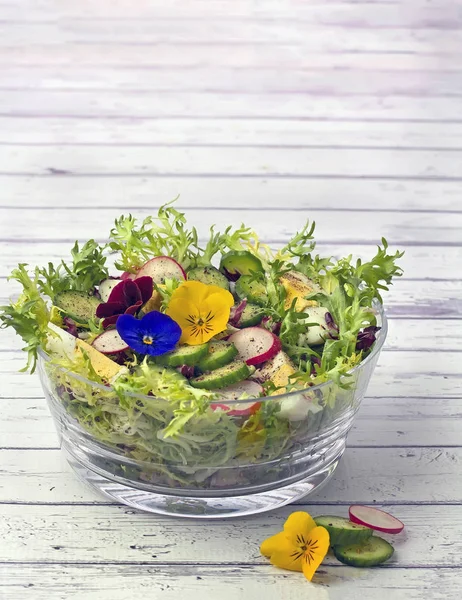 Biologische salade versierd met eetbare pansy bloemen op houten rug Stockfoto