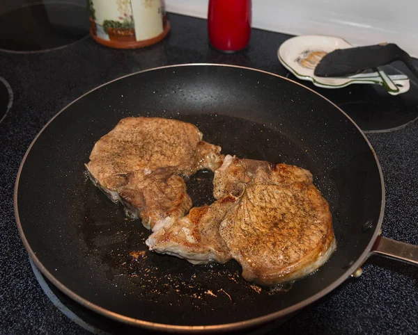 Koekepan met pork chops op de top van de kachel. — Stockfoto