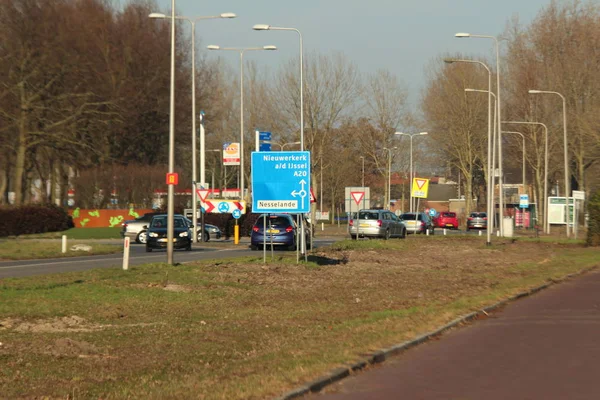 Hoofdweg üzerindeki mavi ve beyaz yön işareti Rotterdam Nesselande ve Nieuwerkerk aan den Ijssel 'e gidiyor.