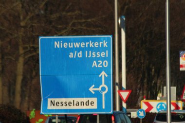 Hoofdweg üzerindeki mavi ve beyaz yön işareti Rotterdam Nesselande ve Nieuwerkerk aan den Ijssel 'e gidiyor.