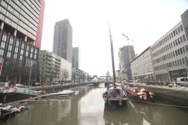 Gökdelenler, eski tekneler ve Rotterdam 'ın merkezindeki Wijnhaven suları etrafındaki iş adamları.