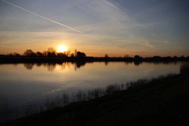 Güneş, Hollandsche IJssel nehrinin suyundan yükseliyor. Park Hitland 'daki hendeğin yanında.