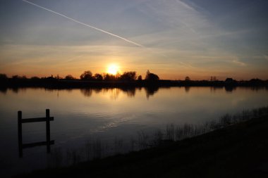 Güneş, Hollandsche IJssel nehrinin suyundan yükseliyor. Park Hitland 'daki hendeğin yanında.