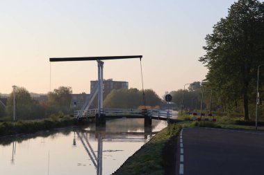 Zuidplaspold Nederland 'ın halka kanalı üzerinde, Nieuwerkerk aan den IJssel kasabasında, güneş doğarken Witte Brug adı verilen tahta asma köprü.