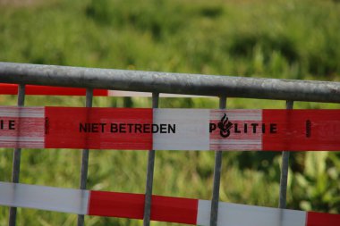Hollanda polisinin kırmızı ve beyaz bariyer bandı suç mahallinde bir bariyer üzerinde