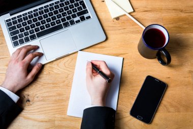 İş notları çalışma masası dizüstü bilgisayar, akıllı telefon ve o taking