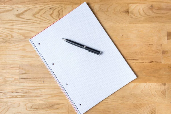 Work desk with note pad and biro on wooden table