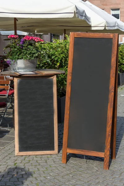 Soporte de pizarra negra sobre madera para un menú de restaurante en el stre — Foto de Stock