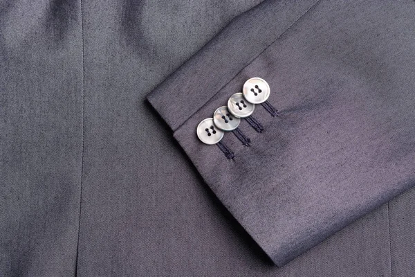 Cuatro botones en una manga de chaqueta de negocios gris —  Fotos de Stock