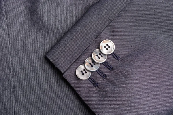 Four buttons on a grey business jacket sleeve