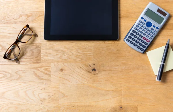 Bureau met tablet, glazen, rekenmachine en notepad op houten — Stockfoto