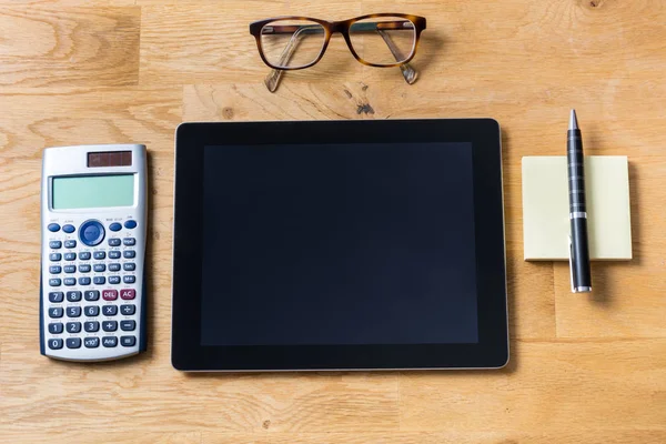 Bureau met tablet, glazen, rekenmachine en notepad op houten — Stockfoto
