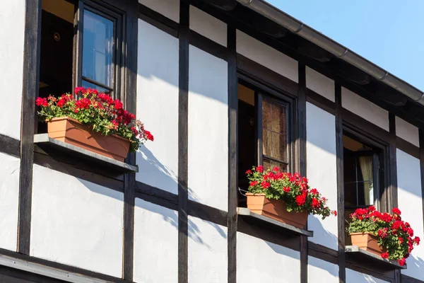 Casa de meia-madeira com persianas e flores — Fotografia de Stock