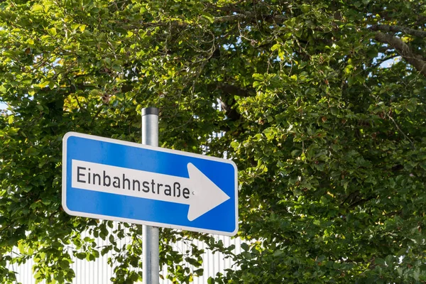 German One Way street sign with trees in the background Stock Picture