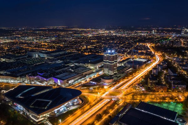 MUNICH, GERMANY - November 3, 2017: The lit BMW headquarters and BMW Welt with light trails from traffic during blue hour from above