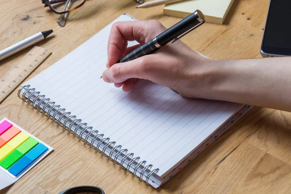 Skriver på ett tomt anteckningsblock med penna och andra tillbehör på en — Stockfoto
