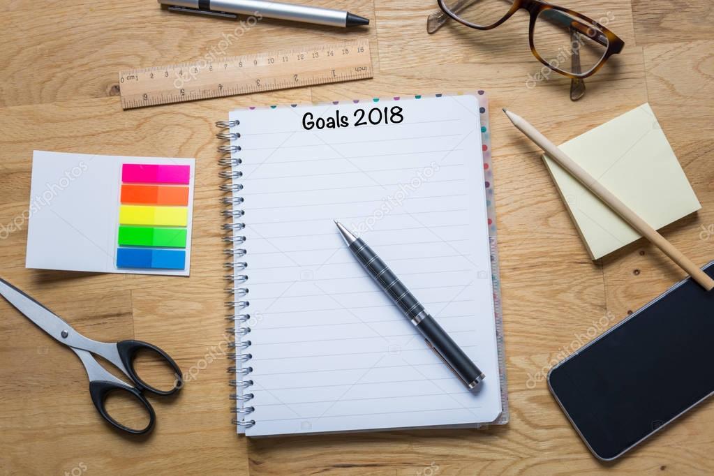 Notepad with goals for 2018 at the top and pen and other accesso