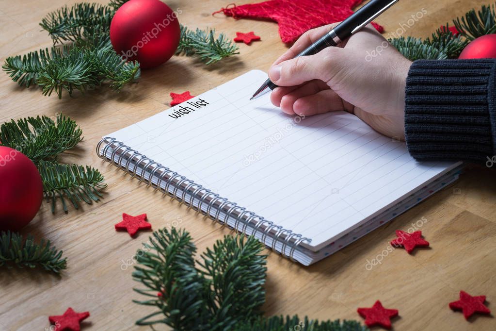 Writing a wish list for Christmas on a notepad with Christmas de