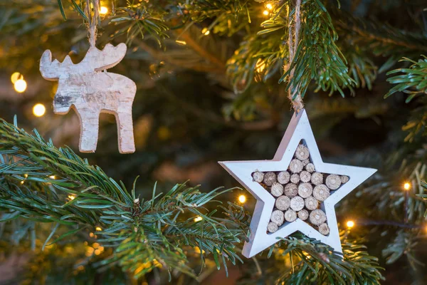 Holzstern und Elchschmuck hängen an einem Weihnachtsbaum mit — Stockfoto