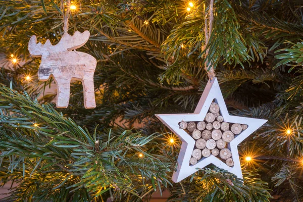 Stella di legno e ornamento alce appeso su un albero di Natale con — Foto Stock