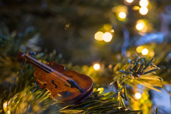 Pequeno ornamento de violino de madeira em uma árvore de Natal com lig fada — Fotografia de Stock