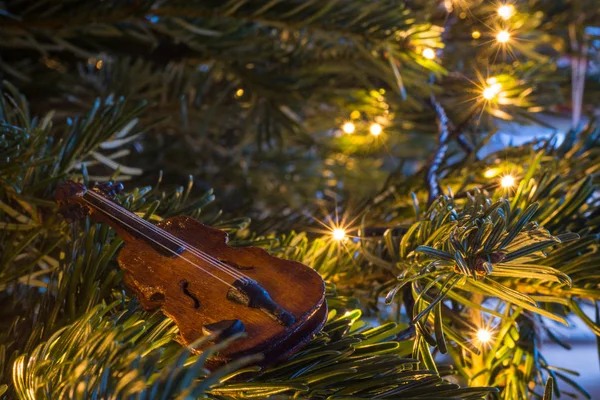 Pequeno ornamento de violino de madeira em uma árvore de Natal com lig fada — Fotografia de Stock