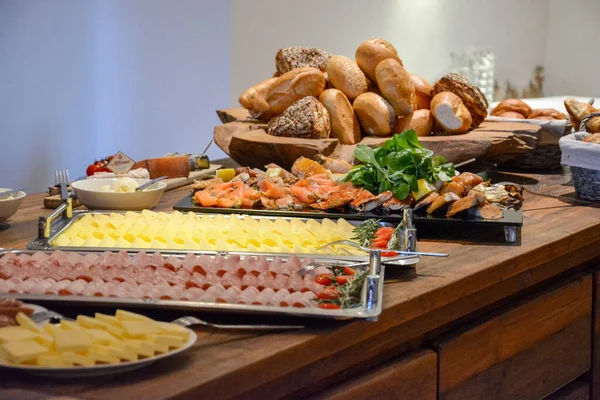 A breakfast buffet with rolls, cheese and several vegetables