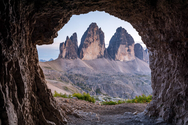 The famous mountains Three Peaks in the Dolomites from a cave during sunset