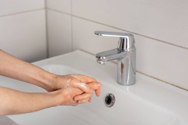Musluk suyunun altında yıkanmadan önce ellerini sabunluyorsun.