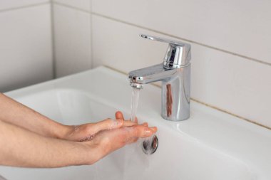 Ellerini musluk suyunun altında sabunla yıka.