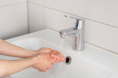 Ellerini musluk suyunun altında sabunla yıka.