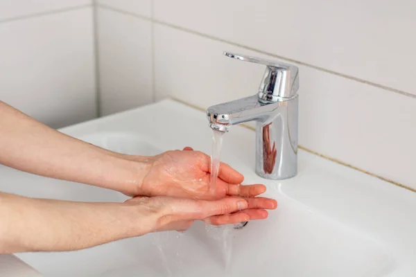 Washing the hands with soap under tap water close up