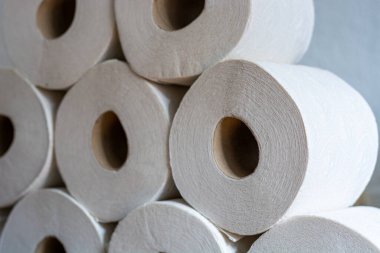 Yan taraftan tuvalet kağıdı ruloları yığılmış.