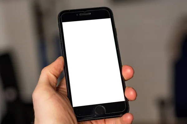 Holding a smartphone with white screen blank ad space close up