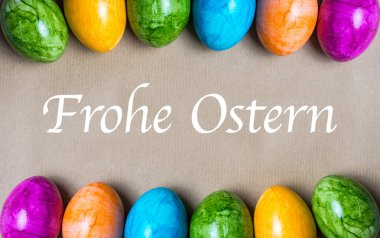 Farklı renklerde Paskalya yumurtalarının iki sınırı. Kahverengi kağıttan arka planda Almanca Mutlu Paskalyalar.