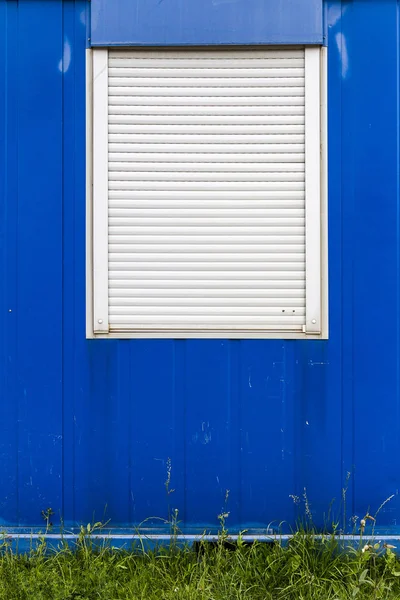 Janela com persianas fechadas em uma parede azul — Fotografia de Stock