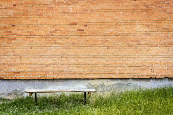 Old wooden bench by red brick wall — Stock Photo, Image
