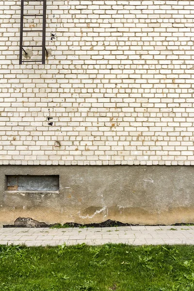 Großes Fragment einer weißen Ziegelmauer mit grünem Gras — Stockfoto