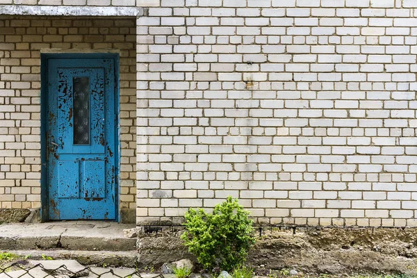 Gammal blå dörr på en vit tegelvägg — Stockfoto