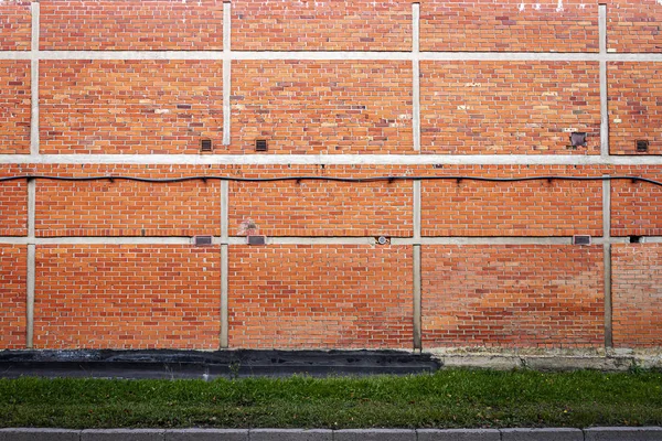 Rode bakstenen muur achtergrond met groene gras — Stockfoto