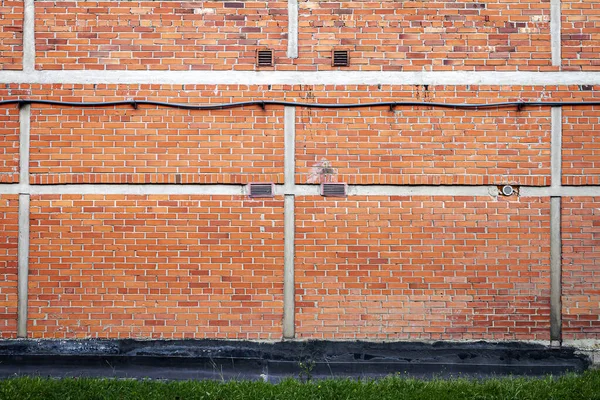 Czerwony ceglany mur tło z zielonej trawie — Zdjęcie stockowe