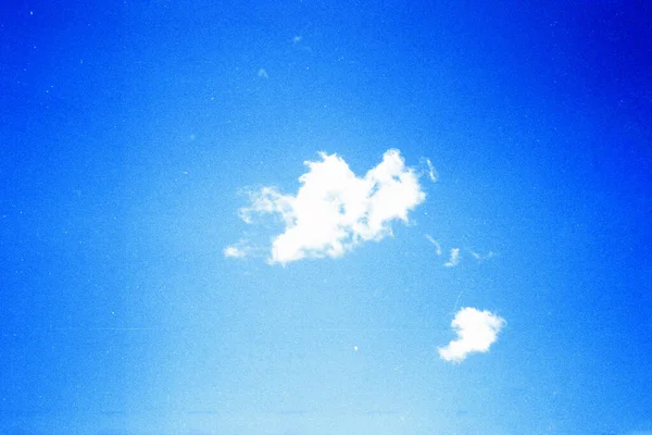 Grunge imagem do céu azul com uma nuvem na textura do filme granulado — Fotografia de Stock