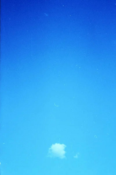 Grunge image of blue sky with a cloud on grainy film texture — Stock Photo, Image