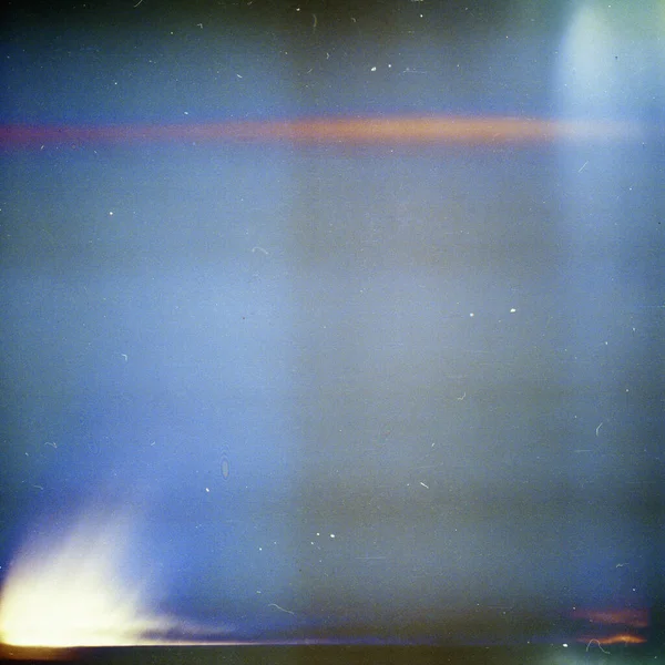 Noisy blue film frame with scratches, dust and light leak. Abstract old film background