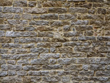 Çeşitli tipte ve kalınlıkta taşlarla örülmüş antik bir duvar.