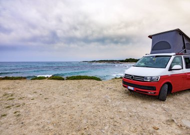 Karavan arabası Cala Liberotto sahilinde, Sardinya 'da park halinde. Baharda boş zaman gezisi
