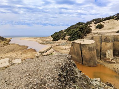Rio Piscinas kumulları aşıp sahili istila ediyor. Rio Piscinas 'taki harabeler denize doğru akarken kırmızımsı bir renk alır ve İtalya' nın Sardunya bölgesindeki antik madencilik faaliyetlerini anımsar.