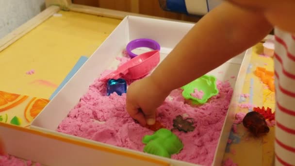 孩子玩粉红色玩沙子 Sandclose 特写镜头的一个2岁的孩子 婴儿玩粉红色的游戏 空间沙子 — 图库视频影像